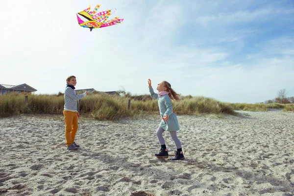 Felices hermanos niños corriendo y divirtiéndose con cometa en la playa — Foto de Stock