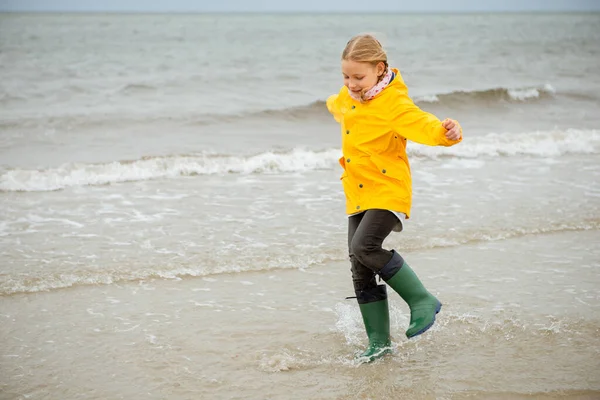 Fröhliches kleines Mädchen läuft in Gummistiefeln auf dem Wasser der Ostsee — Stockfoto