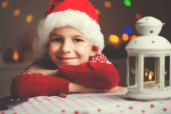 圣诞节儿童给圣诞老人写封信，在红色的帽子 — 图库照片