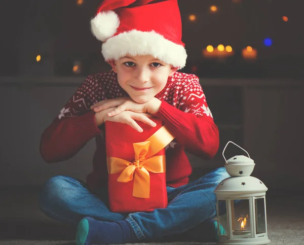 Schattige kleine jongen in rode hoed met gift en latern wachten Santa C — Stockfoto