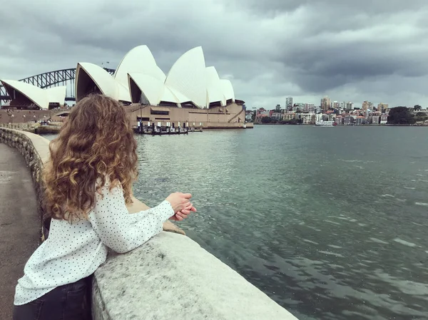 Девушка с вьющимися волосами наслаждается видом на Сиднейскую оперу — стоковое фото