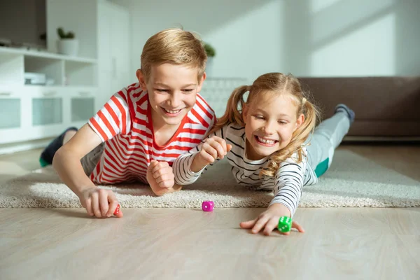 Portret van twee vrolijke kinderen die op de vloer liggen en spelen — Stockfoto