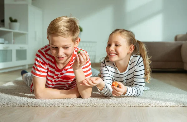 Portrait of two cheerful children laying on the floor and playin — Stock Photo, Image