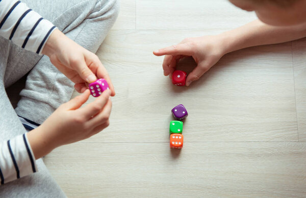 Two clever children study mathematics playing with dices on the 