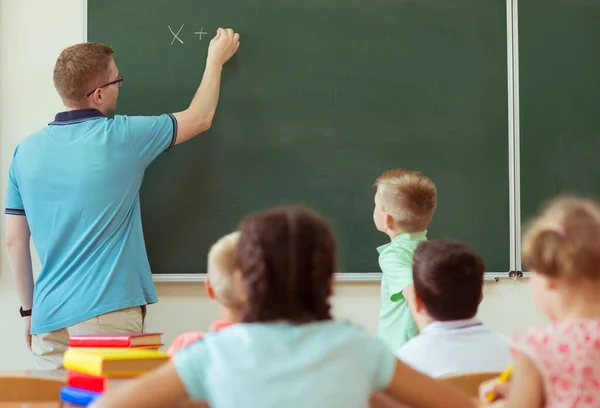 Niño de la escuela con su profesor en la pizarra en la lección de matemáticas en —  Fotos de Stock