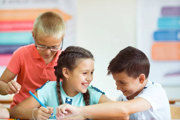 Joyeux élèves du primaire assis au bureau et joyeux discuter — Photo