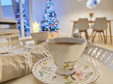 Tepside t-shirt bardaklarının yakın plan fotoğrafı ve arkasında Noel ağacı var.