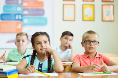 Tatlı okul çocukları duri sınıfında çalışır ve soruları cevaplarlar.