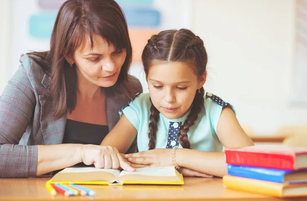 Jong mooi leraar met schoolmeisje lezen boek in de clas — Stockfoto