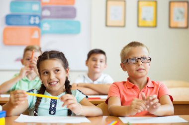 Tatlı okul çocukları duri sınıfında çalışır ve soruları cevaplarlar.