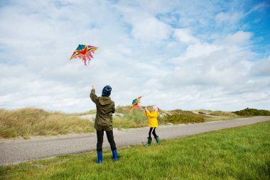 Mutlu kardeşler çocuklar koşuyor ve uçurtmayla eğleniyorlar.