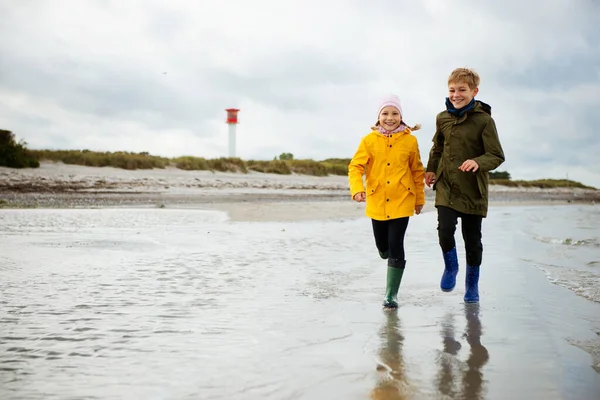 Deux enfants heureux courir et sauter sur l'eau de la mer Baltique dans — Photo