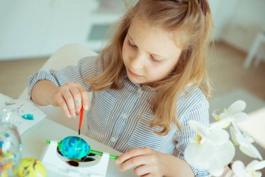 Sevimli küçük sarışın kız boyama paskalya yumurtaları