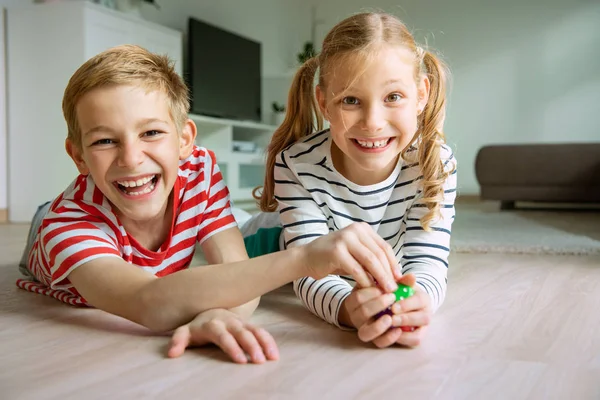 Portret van twee vrolijke kinderen die op de vloer liggen en spelen — Stockfoto