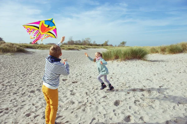 Gelukkig broers en zussen kinderen hardlopen en plezier hebben met vlieger op beac — Stockfoto