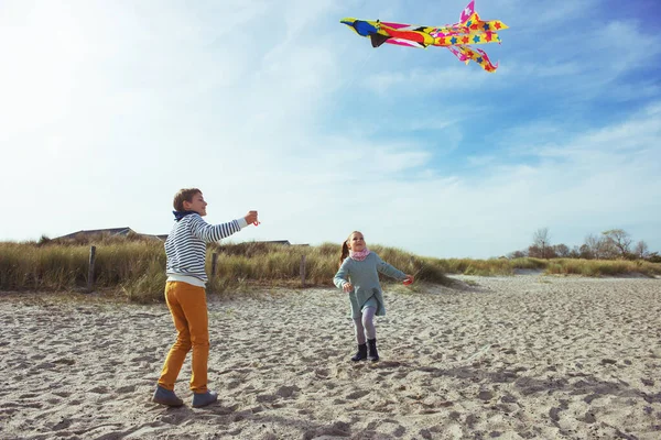 Glückliche Geschwister Kinder laufen und haben Spaß mit Drachen auf Beac — Stockfoto