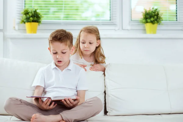 Hermano pequeño y hermana leyendo libro en casa — Foto de Stock