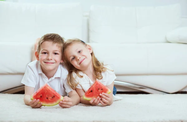 Dwoje szczęśliwych dzieci bawiących się i jedzących arbuza — Zdjęcie stockowe