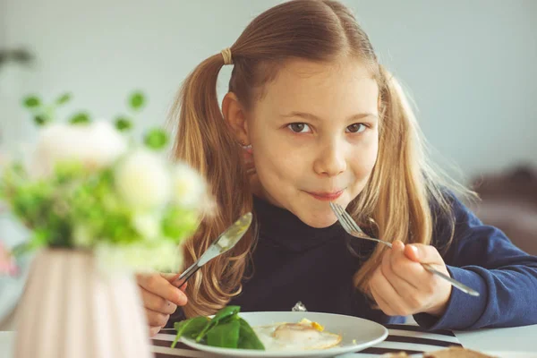 Menina adolescente loira bonito comer ovos benedict com faca e garfo — Fotografia de Stock