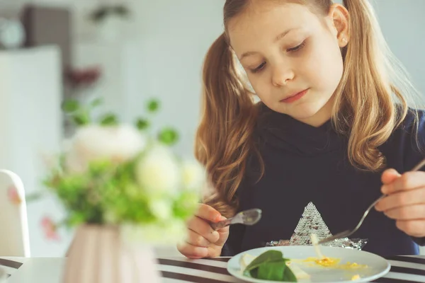 Linda chica adolescente rubia comiendo huevos benedicto con cuchillo y tenedor —  Fotos de Stock