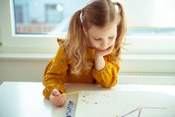 Jolie petite fille payant avec un crayon coloré et un pinceau — Photo