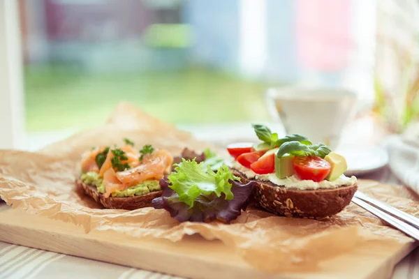 Tostadas Integrales Con Aguacate Tomate Salmón Sobre Tabla Cortar Madera — Foto de Stock