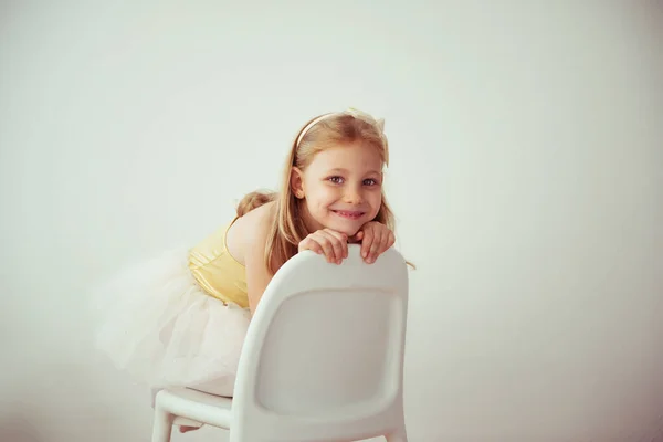 漂亮的金发小女孩穿着芭蕾裙坐在那里 头发上有个蝴蝶结 — 图库照片