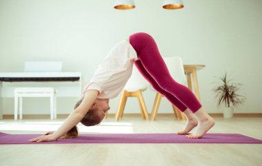 Koronavirüs karantinası sırasında evde yoga yaparken oldukça mutlu bir kız çocuğu.
