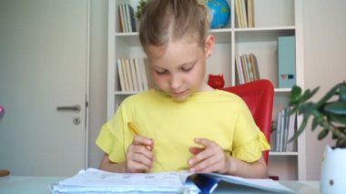 Evdeki masada ödev yapan sevimli küçük kızın yavaş çekim videosu.