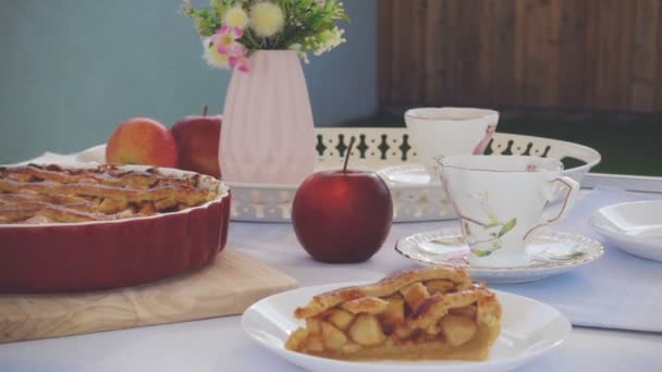 焼きたてのアップルパイのスローモーションビデオ 居心地の良いテラスで自宅でテーブルの上の紅茶と花のカップ — ストック動画