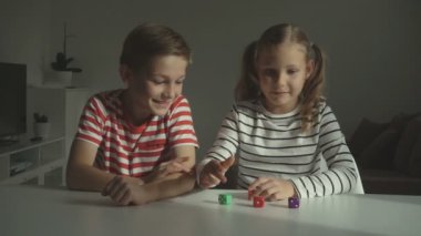 Evde zarlarla oynayan iki mutlu çocuk.