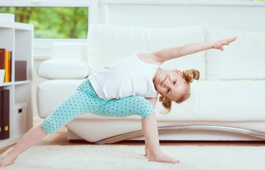 Evde sabah egzersizi ve yoga yapan sevimli küçük kız çocuğu.