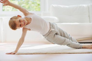 Mutlu küçük çocuk evde spor yapıyor.
