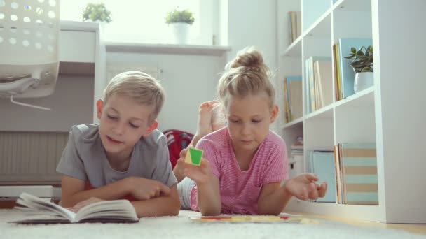 Skolåldern Bror Och Syster Läser Bok Hemma Liggande Golvet — Stockvideo