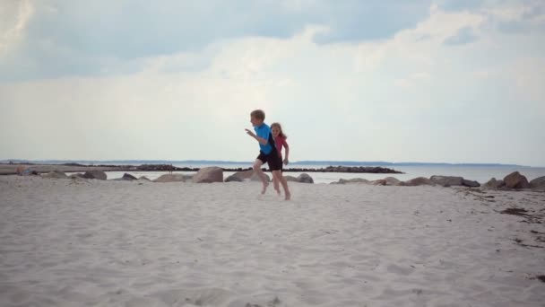 Neoprene Mayo Giymiş Kumsalda Koşan Dalgalarla Kumla Oynayan Iki Çocuğun — Stok video