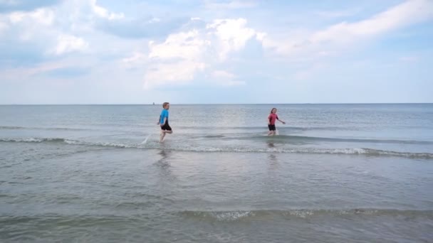 Neoprene Mayo Giymiş Kumsalda Koşan Dalgalarla Kumla Oynayan Iki Çocuğun — Stok video