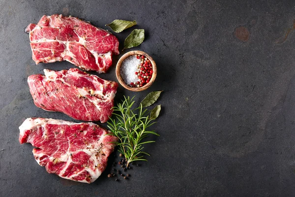 Carne de porco com temperos em uma placa preta — Fotografia de Stock