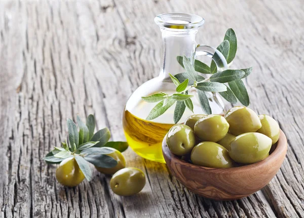 Оливковое масло и оливки на деревянной доске — стоковое фото