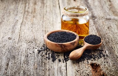 Ahşap arka plan üzerinde siyah kimyon yağı