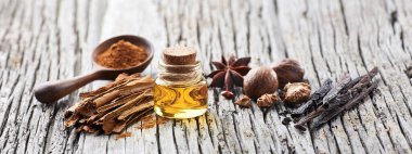 Ahşap zemin üzerinde baharatlar olan bir şişe gerekli yağ. Tarçın, vanilya, hindistan cevizi ve anason..