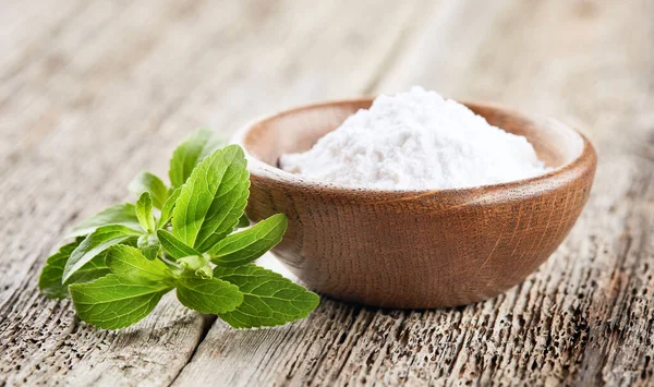 Stevia plant with powder on wooden background