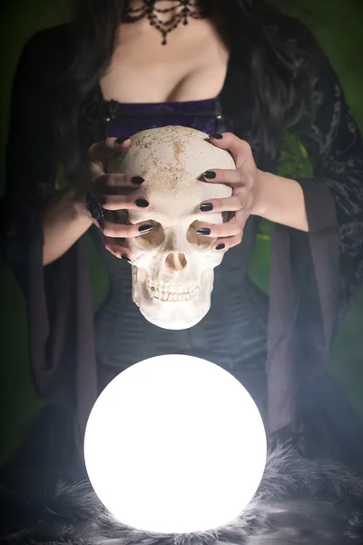 Ведьма с длинными ногтями держит человеческий череп — стоковое фото