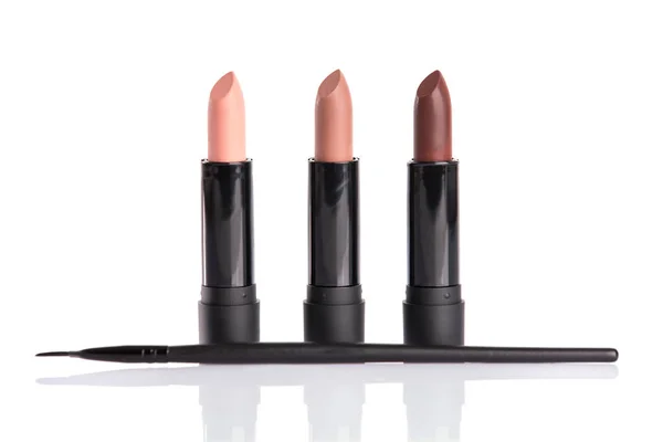 Three lipsticks and makeup brush — Stock Photo, Image