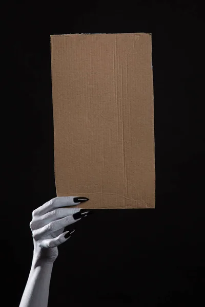 Mão com pregos pretos segurando papelão — Fotografia de Stock