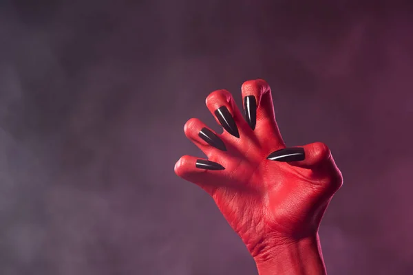 Rote Teufelshand mit schwarzen Nägeln — Stockfoto