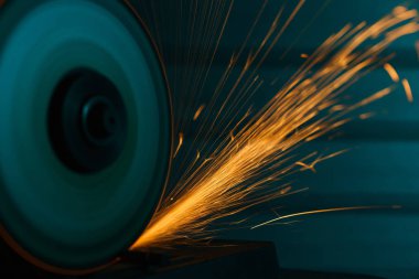 Bir açı öğütücü ile yakın çekim çekim metal arka plan üzerinde parıldıyor 