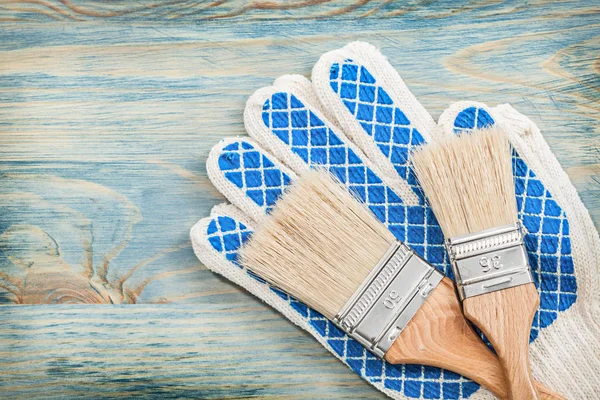 Blue safety gloves and paint brushes — Stock Photo, Image