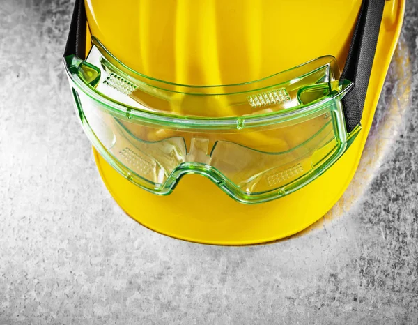 Close up view of safety hard hat and transparent plastic glasses — Stock Photo, Image