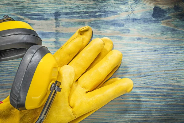 Lederen veiligheidshandschoenen ruis vermindering oorkappen op houten plank c — Stockfoto