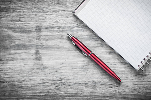 Checked blank notepad ball-point pen on wood board office concep
